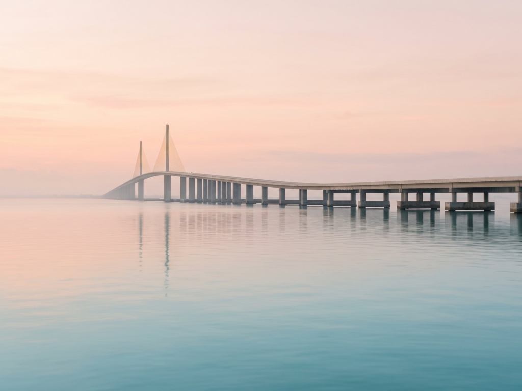 Low spans stretch to the horizon over calm water with two tall pylons visible beyond.